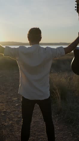 man with guitar at sunset by the water