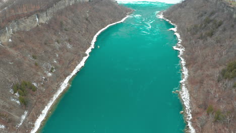 Aerial-shot-of-gorgeous-icy-river-flowing-with-teal-green-waters