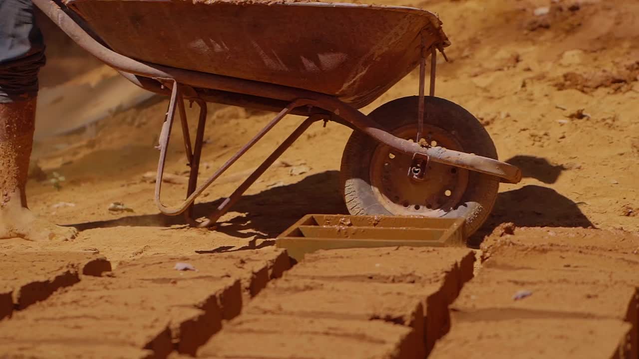 Construction worker creating adobe bricks with wheelbarrow and wooden mold in Chapada dos Veadeiros, highlighting traditional building methods and local craftsmanship in Brazil