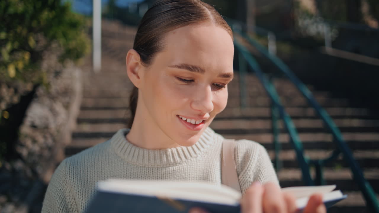 Carefree woman reading book at city park closeup. Happy girl holding notebook