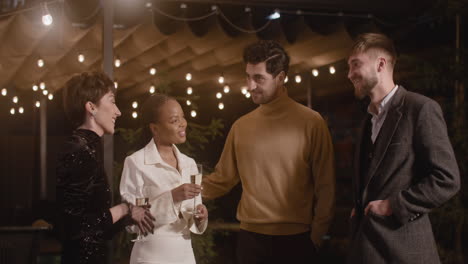 group of four multiethnic friends talking to each other at the new year's eve party