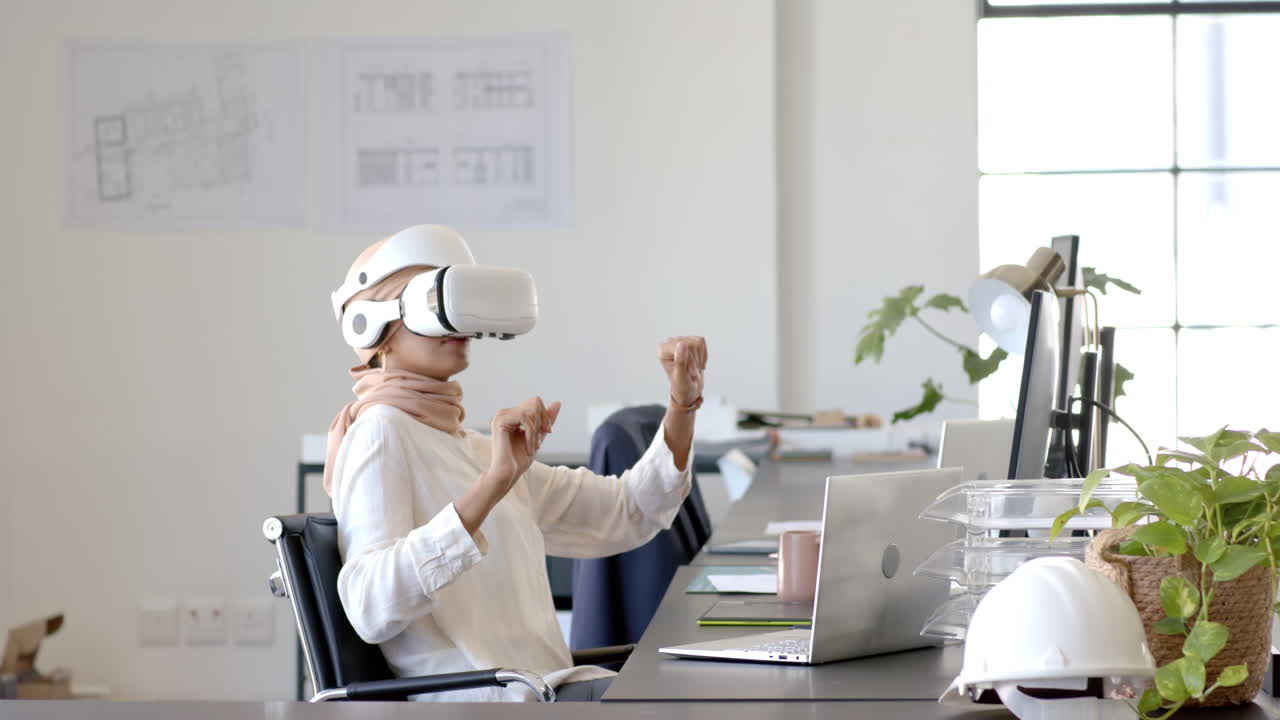 Using VR headset, businesswoman sitting at desk with laptop in modern office