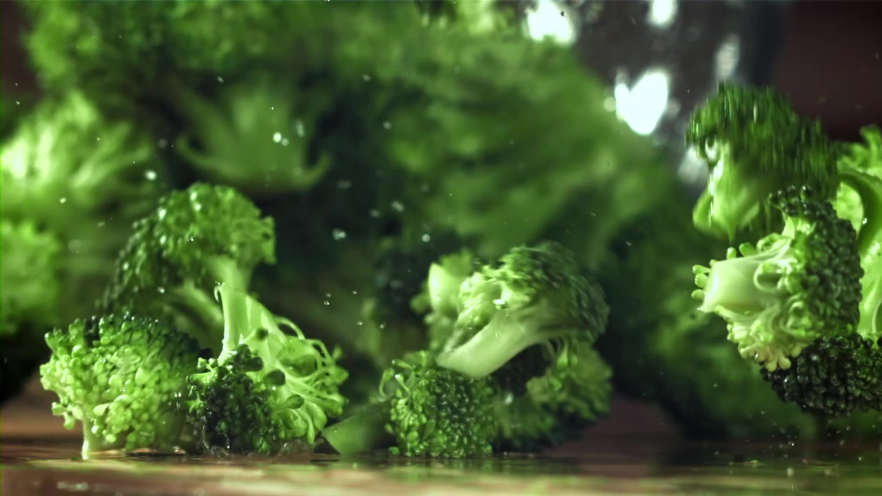 Fresh Green Broccoli Florets Falling in Slow Motion with Water Splashes
