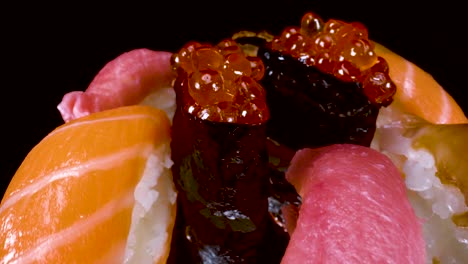 macro view moving over rotating nigiri sushi selection on black reflective glass background, toro tuna, salmon, lemon fish, salmon roe, and bbq eel