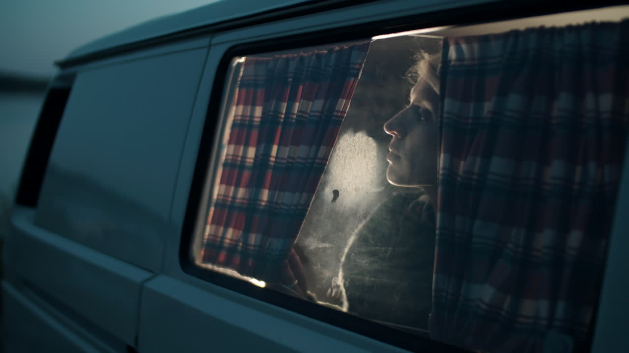 저녁에 캠퍼 밴의 창문을 통해 바라보는 여자