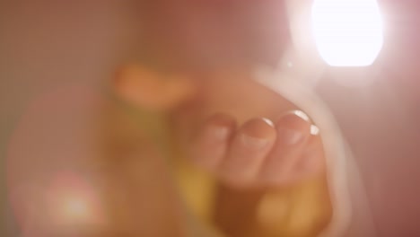 긴 머리카락과 수염을 가진 남자 의 백라이트  ⁇  은 예수 그리스도 의 형상 이 카메라 를 향해 우정을 표시 하는 손 을  ⁇ 고 있다