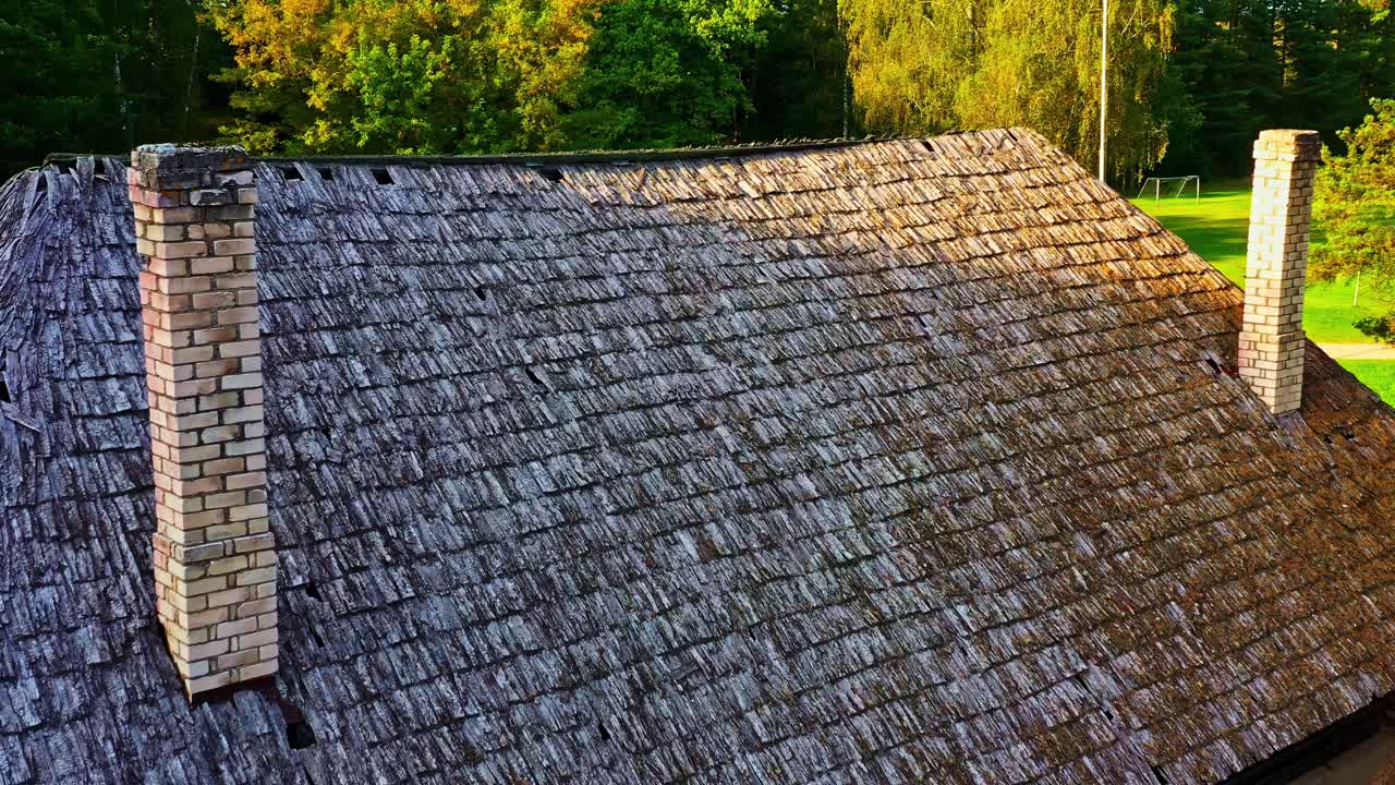 Historic building with wooden shake shingle roof and twin chimneys in aerial view