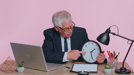 senior smiling businessman showing time on wall office clock, ok, thumb up, good approve success