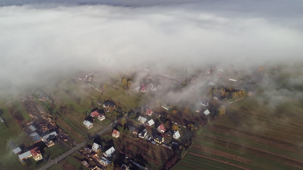 Nubi basse coprono una piccola città rurale nella campagna polacca, ripresa aerea