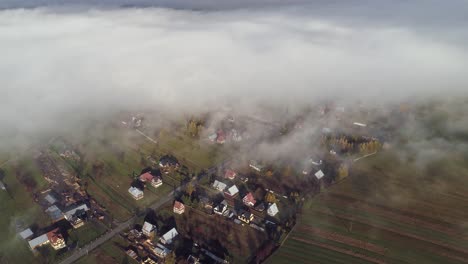 Ground-clouds-cover-small-rural-town-in-countryside-of-Poland,-aerial