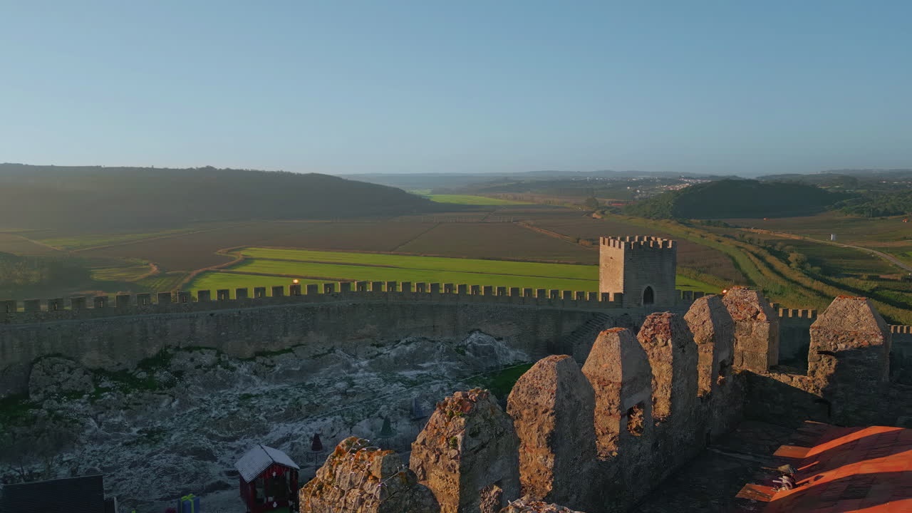 Mura del castello che si estendono su una valle verde in campagna, ripresa con drone. Paesaggio suggestivo.
