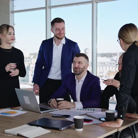 collaborating team of men and women in the office. friendly people co working and discussing ideas. city scenery at the background