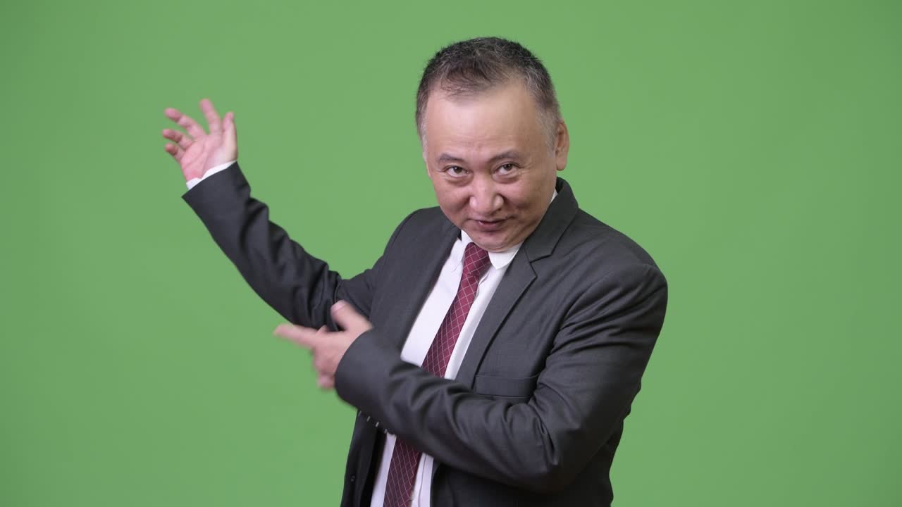 성숙한 일본인 사업가가 무언가를 보여주고 있습니다.