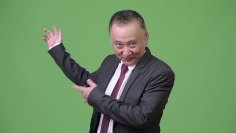 un hombre de negocios japonés maduro mostrando algo.