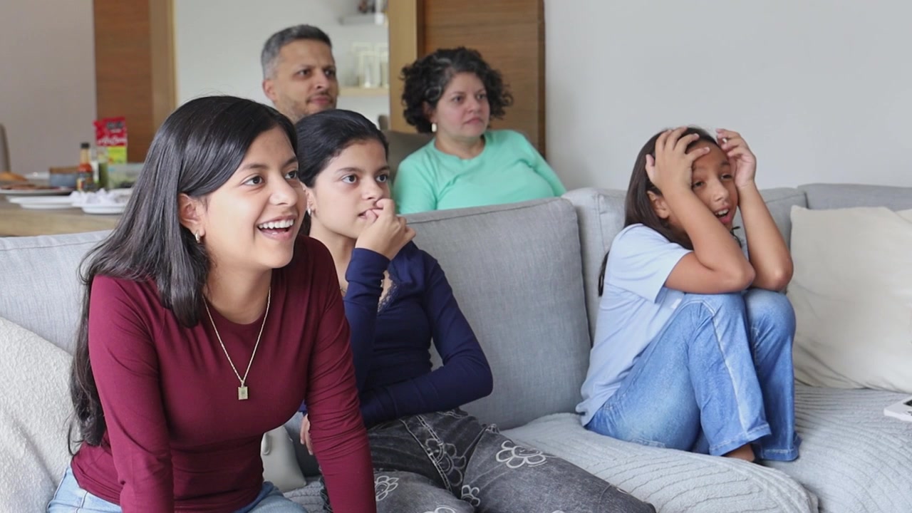 Familia viendo la televisión juntos en la sala de estar