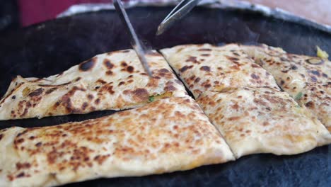 slicing freshly cooked flatbread on a hot griddle