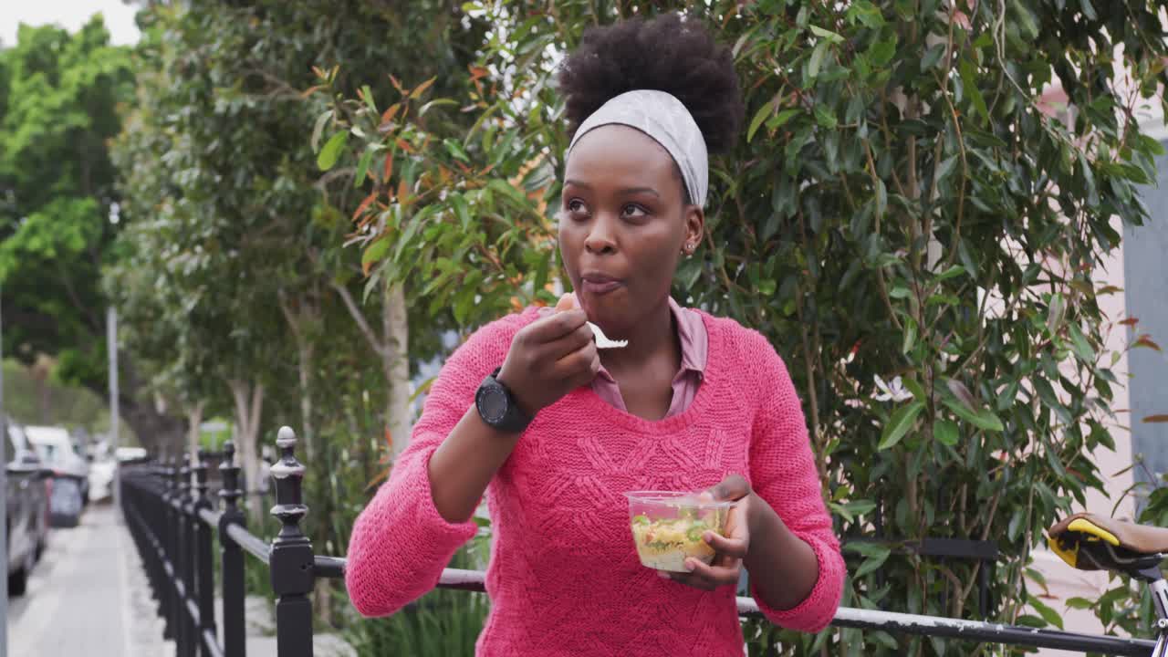 African american eating a salad in street