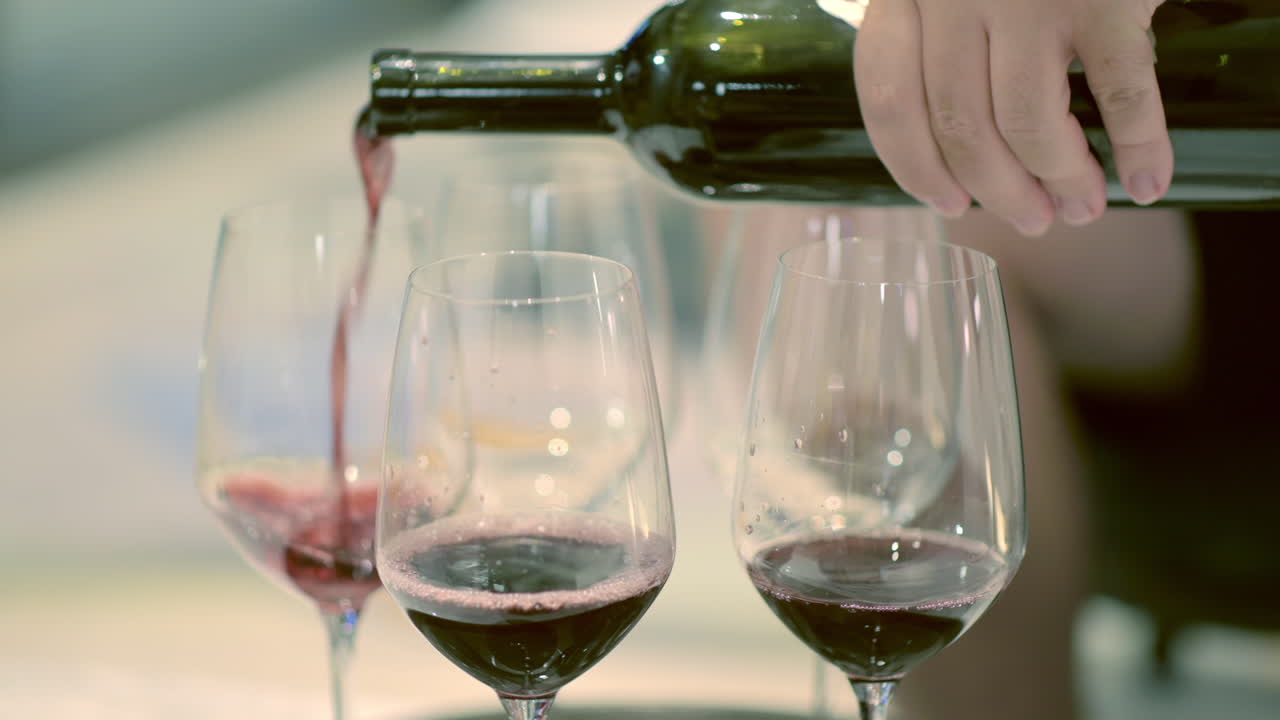 Primo piano di un uomo che versa del vino rosso nei bicchieri