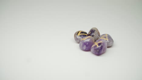 five purple birthstones with engraved symbols and letters on top - close up shot