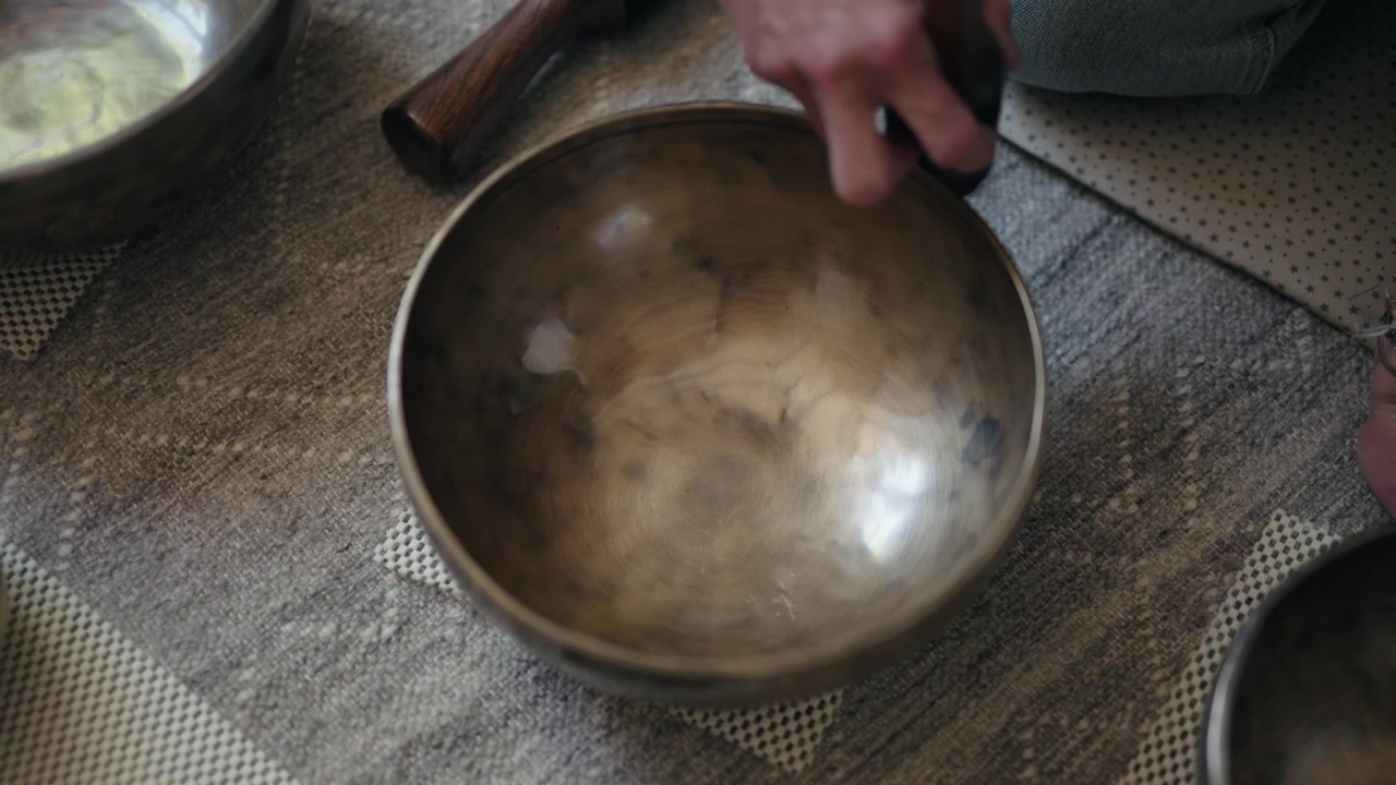 Ripresa dall'alto di una mano che fa girare un martelletto intorno a una campana tibetana