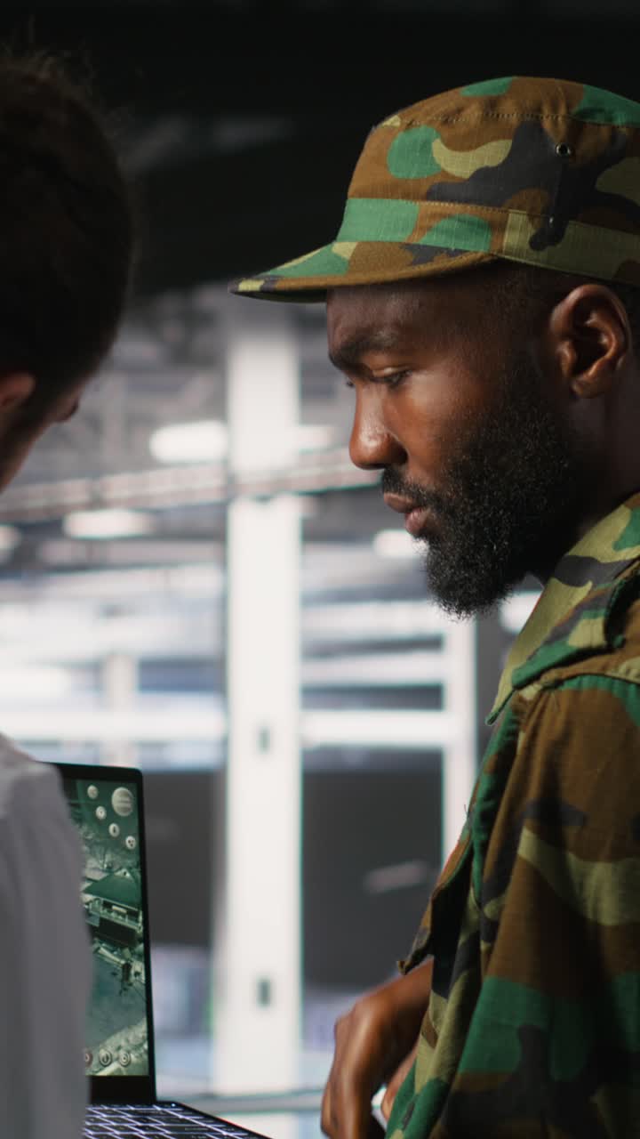 Vertical video Military experts in data center reviewing drone surveillance feed on laptop