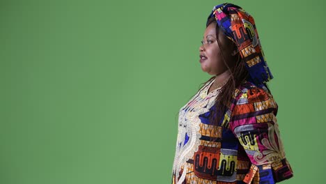 overweight beautiful african woman wearing traditional clothing against green background