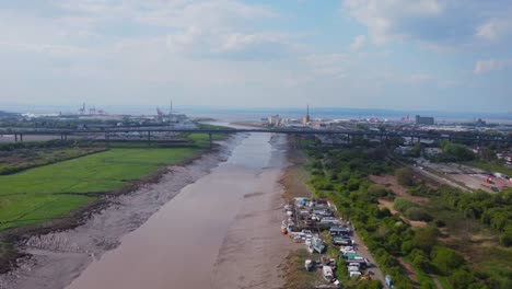 Slow-drone-dolly-shot-over-muddy-Bristol-River-Avon-heading-toward-M5-Avonmouth-Bridge-with-Avonmouth-and-Severn-Estuary-in-the-distance