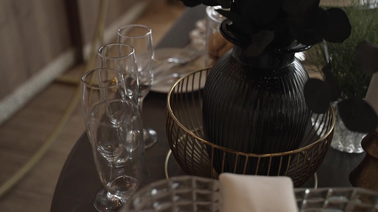 Tabletop with stacked wine glasses, a decorative black vase, and a gold tray in an elegant setup