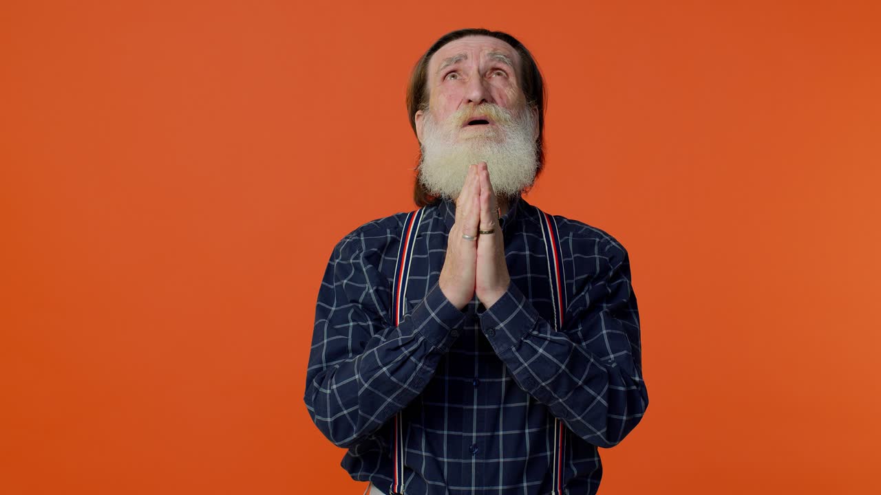 Mature old man praying to God making wish, asking with hopeful imploring expression, begging apology