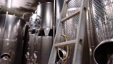 Tanques-De-Acero-Inoxidable-Brillante-En-Bodega-Utilizados-Para-La-Fermentación-Del-Vino,-Inclinación-Hacia-Arriba