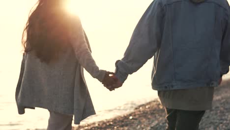 couple walking hand-in-hand on the beach at sunset