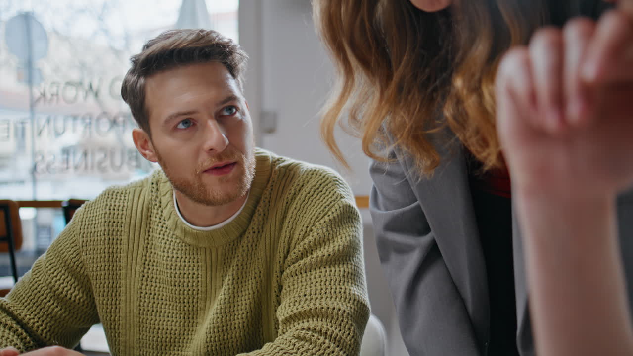 Two colleagues discussing startup at windows interior closeup. Coworkers talking