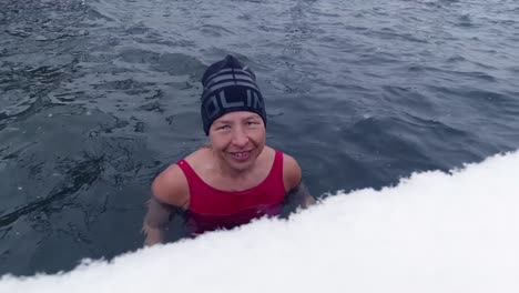 close-up of a woman taking an ice-bath in a lake during snowfall