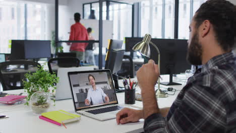 hombre de oriente medio teniendo una videollamada con un colega masculino en una computadora portátil en la oficina