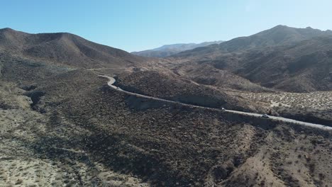 Many-cars-drive-on-desert-highway-in-California,-aerial-ascend-shot