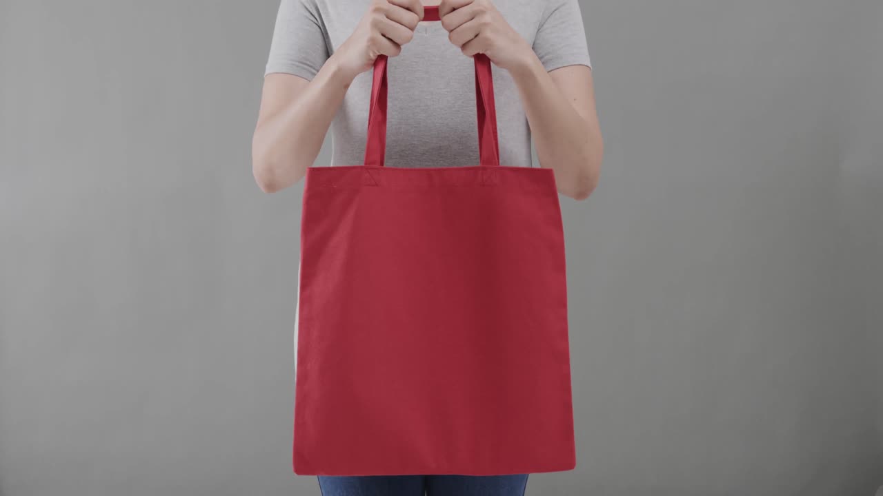 ⁇ 색 티셔츠를 입은 백인 여성이 회색 배경에 빨간 가방을 들고, 복사 공간, 슬로우 모션
