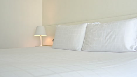 double bed with white headboard and candid sheets and pillows in hotel room