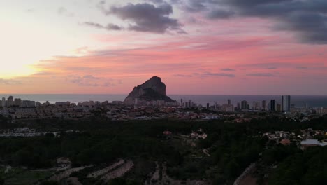 imágenes de drones de lapso de tiempo de un hermoso amanecer de color rosa y naranja sobre la ciudad de calpe, españa, que muestra el hito natural peñón de ifach y el mar mediterráneo en el fondo