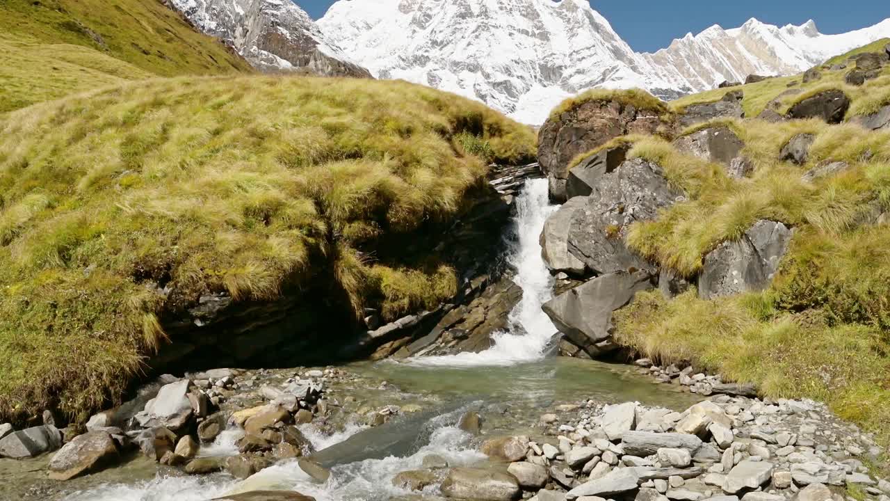 Waterfall Stream and Himalayas Mountains in Nepal, Snowcapped Mountain Top Landscape and Flowing River Scenery in High Altitude Terrain in Annapurna Region at Annapurna Base Camp