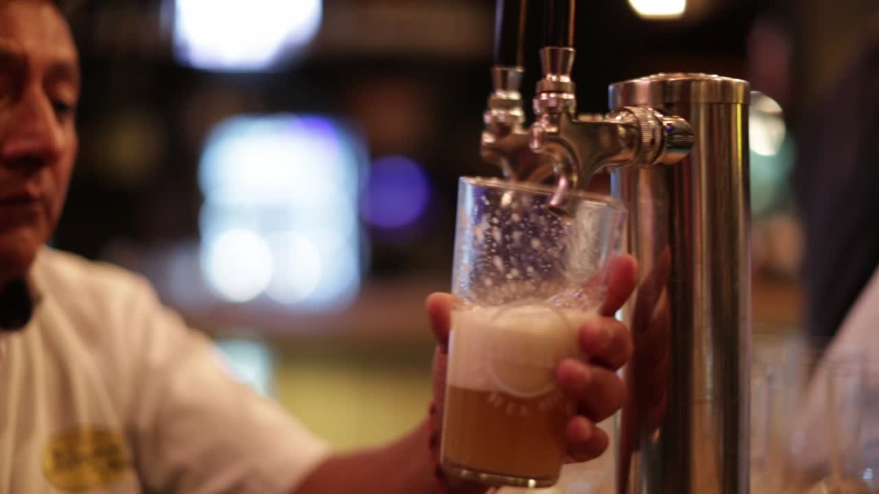 Bartender's hand filling a glass with beer from the tap