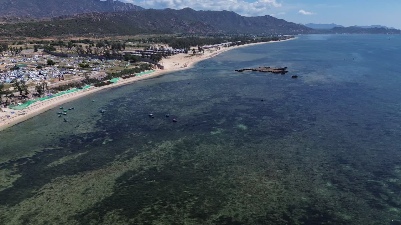 Aerial semi orbit showcasing traditional fishing boats anchored in the bay of Ninh Hải District under clear blue skies.
