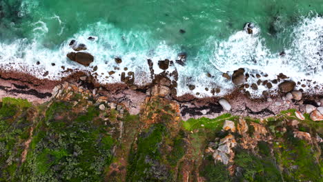 South-Africa-rugged-coastline-small-beach-town-Smitswinkel-Bay-Cape-of-Good-Hope-Simon's-Town-aerial-drone-cinematic-homes-surf-wave-green-lush-spring-summer-deep-aqua-blue-ocean-up-motion