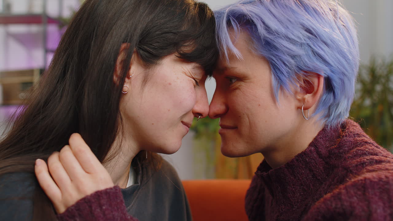 Closeup portrait of two young lesbian women family couple girls embrace hug each other at home