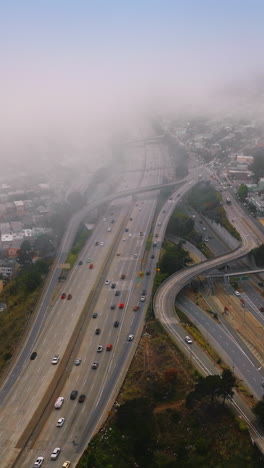 big city panorama covered with thick fog at daytime. multilane roads with cars going into hazy horizon of san francisco. top view. vertical video