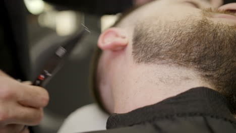 barbero recortando el cuello y la barba de un cliente