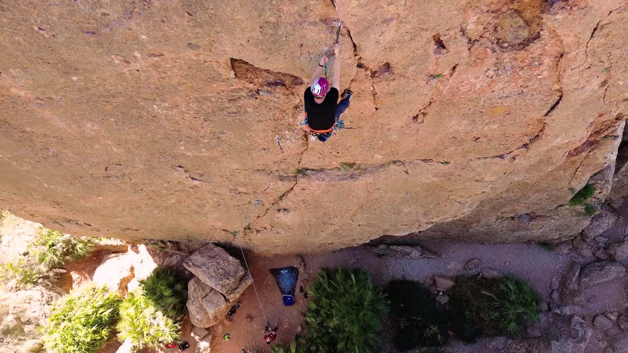 Luftaufnahme eines Mannes beim Felsklettern und eines Sportlers beim Abseilen am Berg in La Panocha, El Valle Murcia, Spanien, mit einer Frau, die sich einen Berg hinabseilt und einen großen Felsen erklimmt.