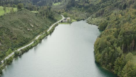 Orilla-Sur-De-La-Presa-Del-Embalse-De-Freibach-En-Austria-Con-El-Restaurante-Griego-Stausewirt-Lejos,-Toma-Aérea-De-Revelación