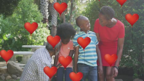 animation oh heart balloons over happy african american family in garden