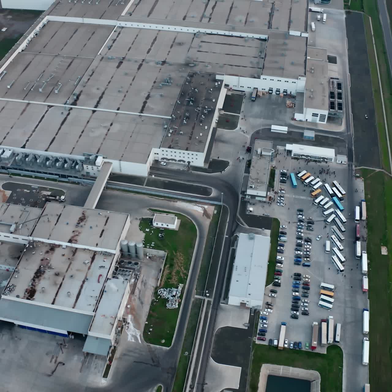 Huge industrial zone on field. Grey roofs of industrial plant among nature. Large territory of manufacturing and car parking near the road. Aerial view.