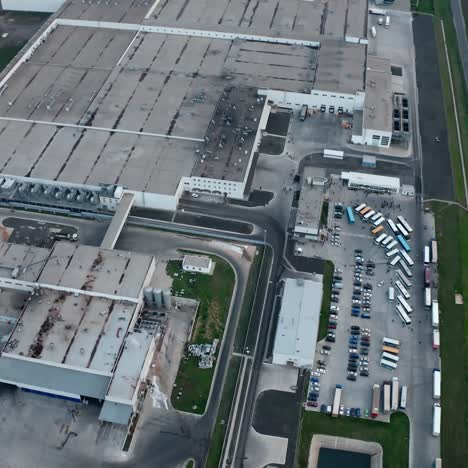 huge industrial zone on field. grey roofs of industrial plant among nature. large territory of manufacturing and car parking near the road. aerial view.